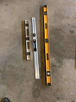Overview of three spirit levels of varying lengths laid on the ground