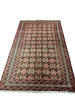 Full view of the Baluchi handmade wool rug showing the geometric patterned field and borders in natural wool and plant-based red, pink, black and white colors.