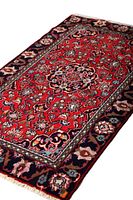 Angle showing entire rug with detailed floral and medallion pattern on red field, navy border with multi-colored flowers.
