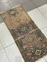 Full view of the vintage Karaja runner rug laid on tiled floor showing geometric and pastel patterns.