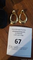 Pair of gold teardrop earrings displayed with auction card