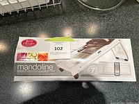 Mandoline slicer box showing brand Benny Olivier and an image of the slicer with vegetable slices.