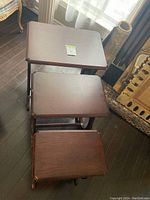 Three solid wood nesting tables arranged one on top of the other showing top surfaces.
