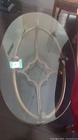 Oval glass top on decorative metal base showing the top view.