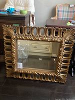 Front view of the square gold-painted mirror with ornate wooden frame and decorative detailing.