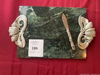 Image of rectangular serving platter with dark green stone base and two decorative pewter handles, accompanied by a matching pewter cutting utensil placed on top.