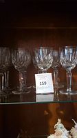 Four Waterford Crystal wine glasses on a glass shelf