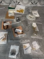15 pieces of jewelry items in original packaging spread on a gray surface.