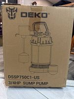 Photo of the DEKO DSSP750C1-US 3/4 HP sump pump in cardboard box showing product illustration and brand logo on side.