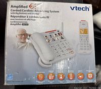 Box front showing the VTech amplified corded/cordless answering system with big buttons and display, model SNS147. Features highlighted include smart call blocker, 50dB audio assist, photo dial, caller ID, digital announcing, and visual ringer indicator.