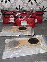 Three packaged red first aid kits behind two sealed bamboo foot files on a countertop.