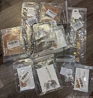10 pieces of new fashion jewelry in original packaging on a wooden surface. Assorted necklaces and bracelets with letter and friendship themed charms.