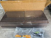 Stack of Paulownia wood shelves with a pack of plastic anchors and screws in front, unopened in plastic.