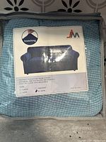 Front packaging of the teal XL sofa cover showing brand JM, fabric composition, size, and description.