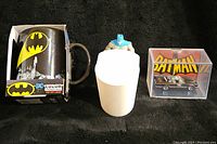Batman color change mug, mini Batman figure, and die-cast Batmobile in case laid out on black background