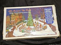 Box showing the Dept 56 All Around The Park Village Animated Accessory Set with winter village scene on cover.