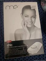 Original boxed Me Chic hair removal device showing product name, key features, and a smiling woman's face in grayscale