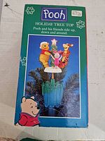 Box showing product name 'Pooh Holiday Tree Top' and illustration of the tree topper with Winnie the Pooh characters