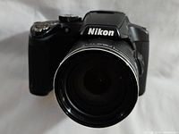 Front view of black Nikon Coolpix camera with lens and Nikon branding visible.