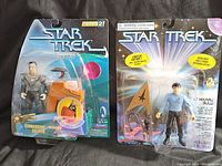Both Star Trek action figures in original sealed packaging, showing Cardassian Soldier figure with blaster and vehicle accessory, and Lt. Hikaru Sulu figure in blue uniform with phaser.