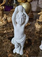 Single view of one unpainted bisque ceramic boy statue, showing detailed facial features, hair, and cloth draping.
