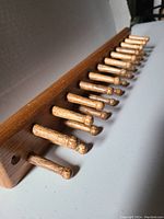 Close-up side angle showing 24 rounded wooden pegs attached to a solid oak wood base with mounting holes at ends.