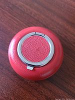 Top view showing chrome circular flip lid with red leather center and outer red leather covering.