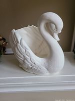White ceramic swan planter pot angled to show detailed feathers and open basin for planting.