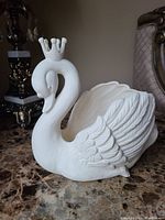 Front angle view of white ceramic swan planter showing texture and crown detail