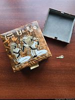 Closed vintage leather jewelry box with Egyptian figures tooled in silver on the top lid, key and snap lock shown beside it.