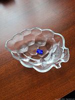 Clear glass grape-shaped candy dish from Studio Nova with textured grape cluster design and leaf accent on side, showing original label at base.