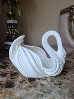 Side angled view of white ceramic swan figurine showing wing detail.