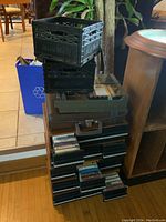 Stack of seven full cassette cases with two black plastic crates on top, showing quantity and storage format.