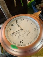 16 inch wall clock with copper-colored frame, white face, and temperature/humidity gauges