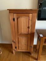 Front view of solid wood pine cupboard with closed door.