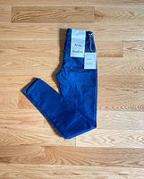 Jeans folded on wooden floor showing front and brand tags