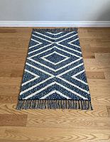 Full view of the modern blue and white geometric runner rug laid flat on hardwood floor showing pattern and fringe ends.