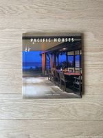 Cover photo of Pacific Houses book, showing a modern patio with dining furniture and ocean view.