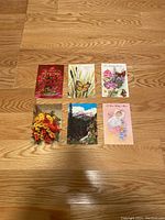 Six vintage greeting cards placed on wooden floor arranged in two rows with floral and nature themes