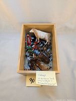 Wooden box containing vintage lead soldiers and various animal figures including horses and a cow, showing the full lot contents.