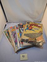 A pile of around 15 vintage DC comic books prominently showing Superboy titles from the 1970s in plastic sleeves.