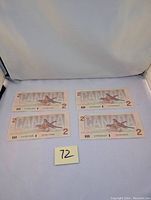 Four Canadian $2 bills laid out flat showing two sets of sequential serial numbers under normal lighting and neutral background.