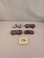 Four vintage redline Hot Wheels cars arranged on white background; show paint wear and redline wheels visible
