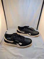 Pair of black and white Reebok Court Advance sneakers shown outside the box.