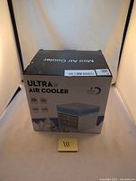 Front view of the boxed Ultra Mini Air Cooler showing product image and branding.