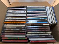 Photo showing a collection of CDs stacked in boxes with visible artist and album titles.