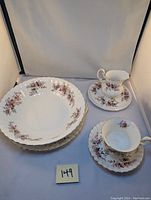 Photo showing three large serving bowls stacked with floral Lavender Rose pattern and gold trim, alongside a teacup with floral and gold detailing, seated on a matching saucer.