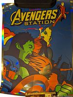Close-up of colorful Marvel Avengers foil poster by Dan Stiles showing Hulk, Iron Man, Captain America and other heroes with holographic foil details and bold text "Avengers S.T.A.T.I.O.N".