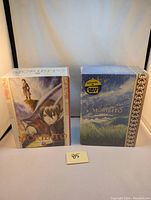 Two sealed DVD box sets of Morbito: Guardian of the Spirit. One box has a blue sky and grass cover with a gold pattern and Best Buy exclusive sticker, the other shows anime characters on a stormy background.