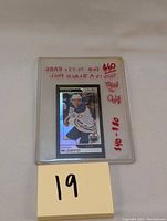 Front view of the Connor McDavid 2017-18 O-Pee-Chee M-77 Black Foil hockey card in protective plastic case with handwritten pricing notes.